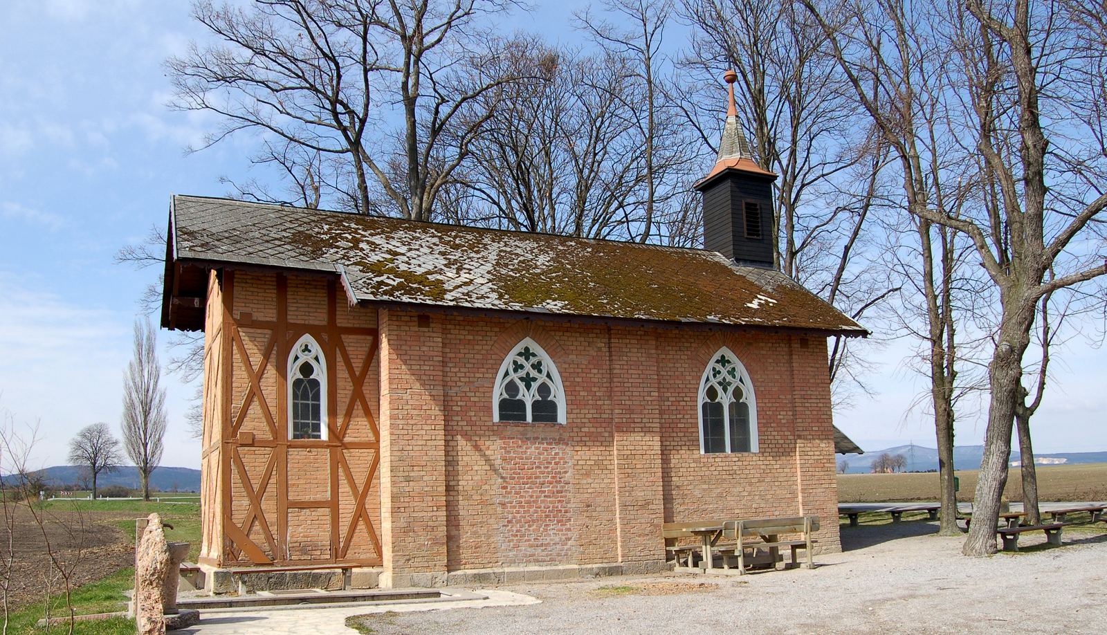 Die Kapelle am Heilsamen Brunnen bei Leobersdorf, Namensgeberin der Apotheke: Ziegelbau mit gotischen Spitzbogenfenstern und kleinem Glockenturm unter kahlen Bäumen